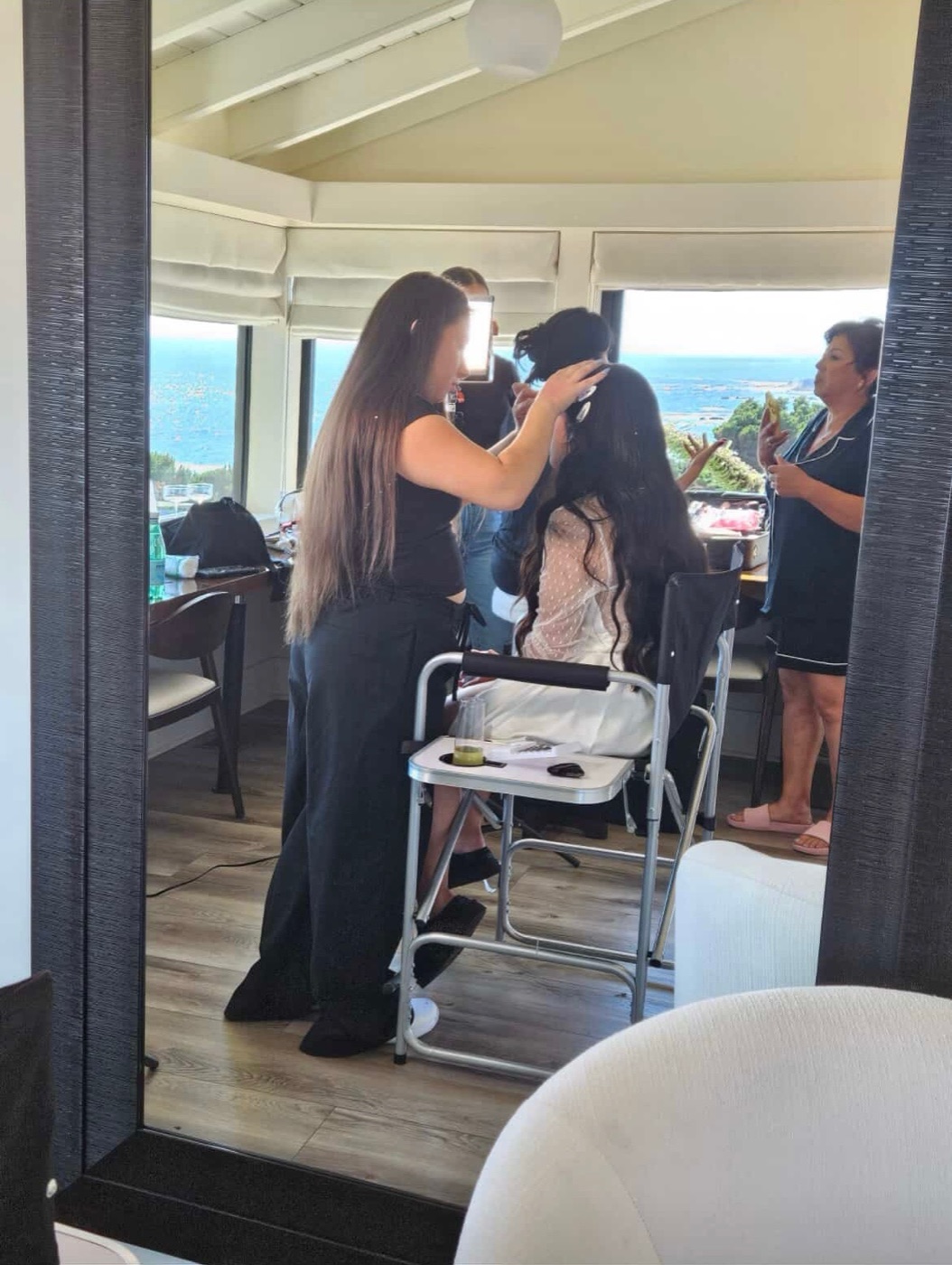 Andrea applying on-location bridal makeup to a seated bride at a coastal Bay Area venue with an ocean view
