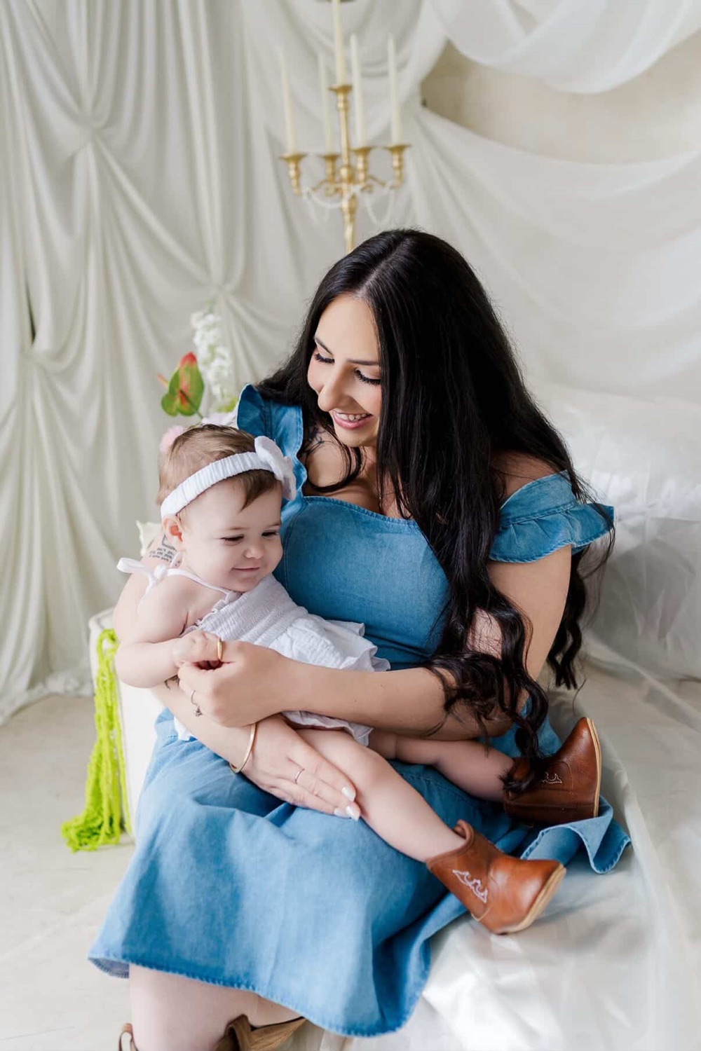 Mom in denim cradling her baby at a family photoshoot, soft glam makeup by Andrea, Bay Area